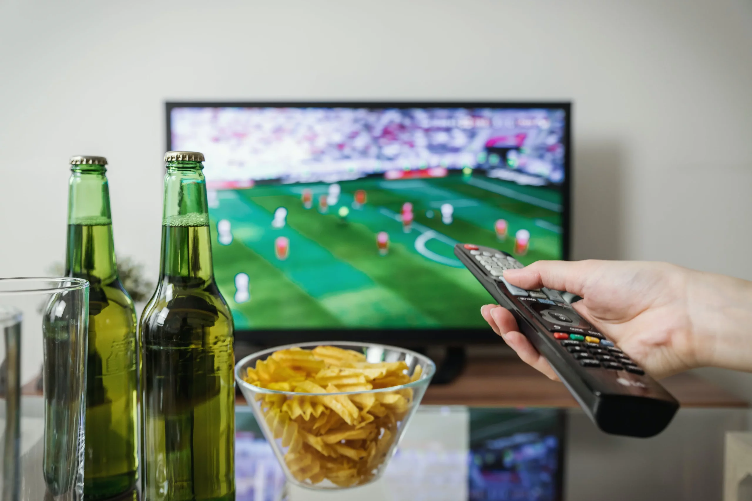 beer and crisps in front of a TV with sports playing